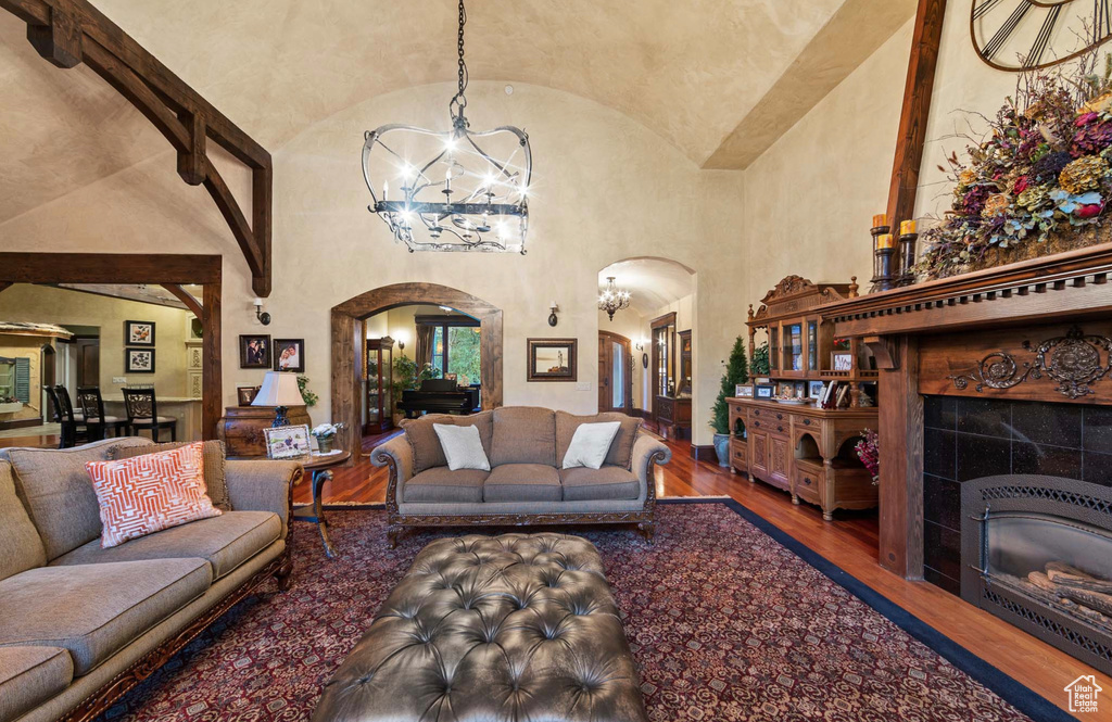 Living room featuring a tile fireplace, a chandelier, high vaulted ceiling, and dark wood-type flooring