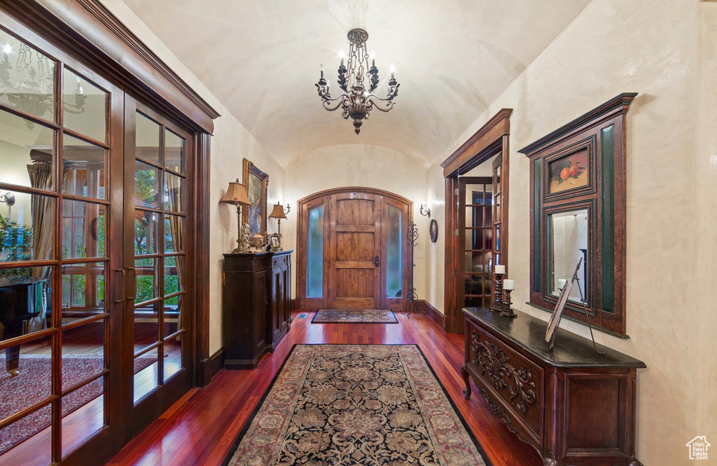 Entryway featuring dark wood-type flooring, a notable chandelier, and french doors
