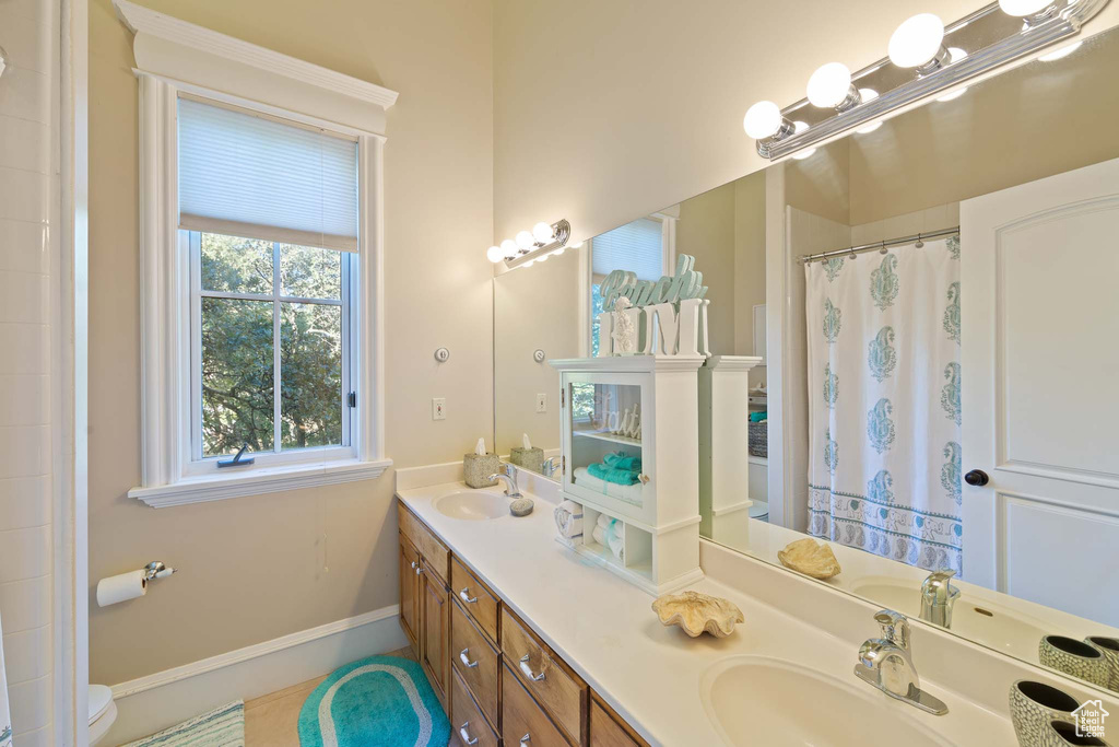 Bathroom featuring dual sinks, toilet, and large vanity