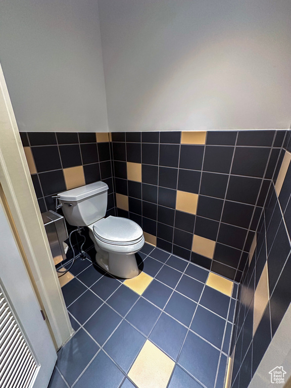 Bathroom featuring tile walls, toilet, and tile flooring