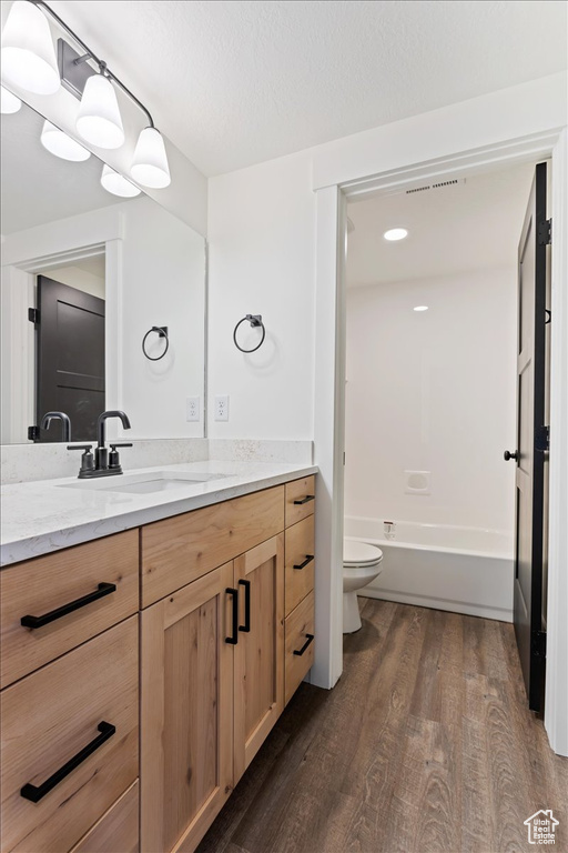 Full bathroom with toilet, bathtub / shower combination, vanity, and hardwood / wood-style flooring