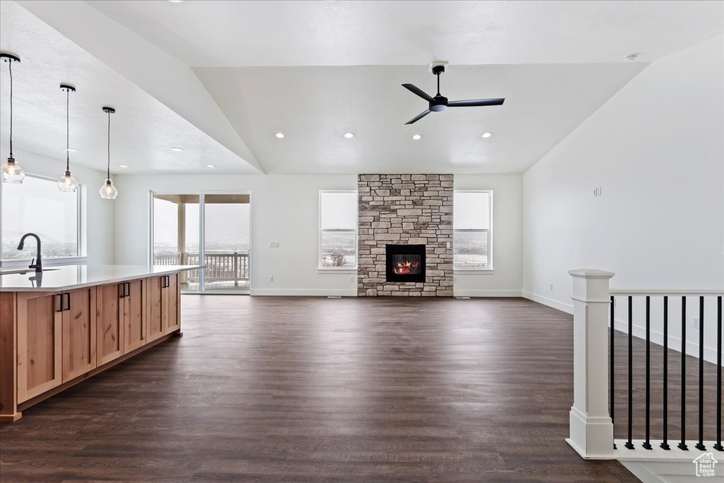Living room featuring lofted ceiling, dark hardwood / wood-style floors, ceiling fan, sink, and a stone fireplace