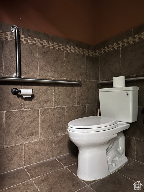 Bathroom with tile floors, toilet, and tile walls