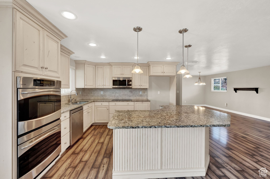 Kitchen featuring light hardwood / wood-style flooring, decorative light fixtures, stainless steel appliances, and backsplash