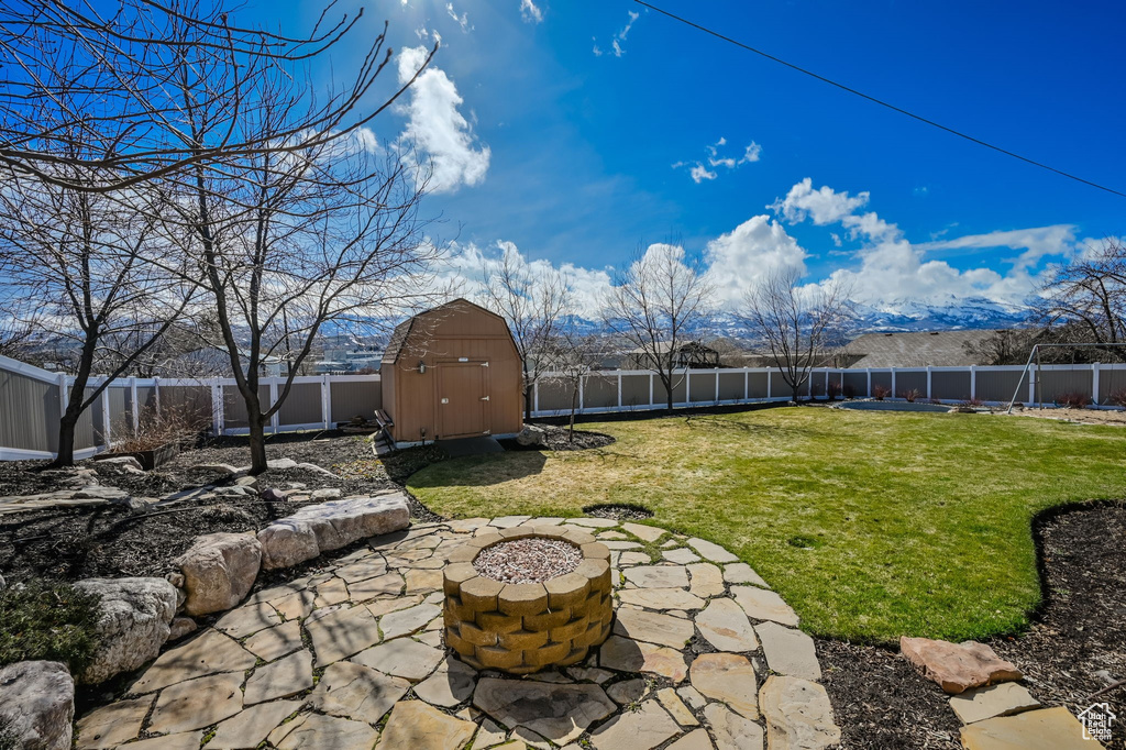 View of yard with a patio, a shed, a mountain view, and an outdoor fire pit