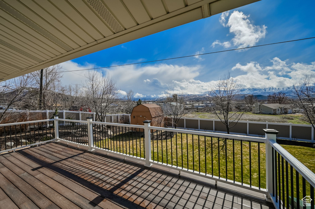 Wooden deck featuring a mountain view, a yard, and a storage unit