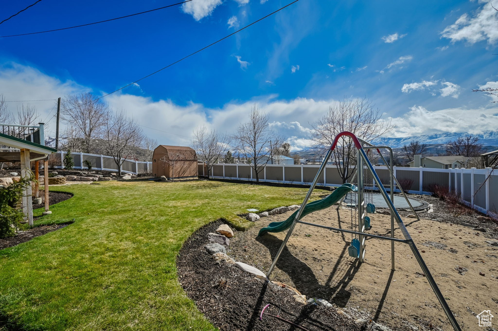 View of yard with a playground and a storage shed
