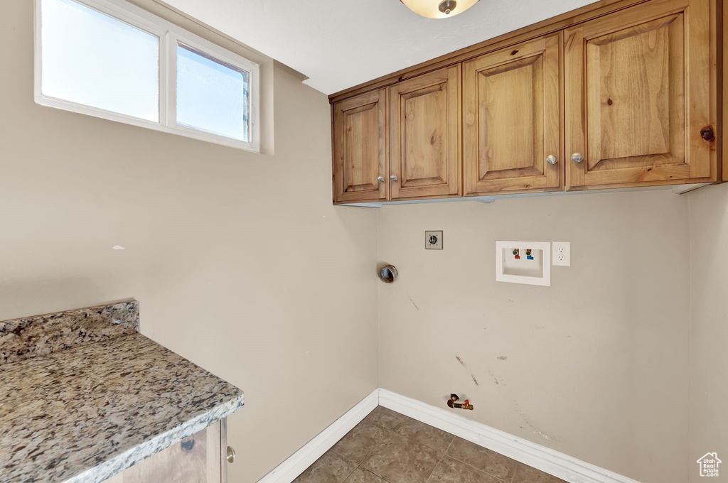 Washroom featuring washer hookup, hookup for an electric dryer, dark tile floors, gas dryer hookup, and cabinets