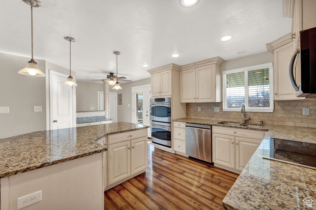 Kitchen featuring backsplash, sink, appliances with stainless steel finishes, and ceiling fan
