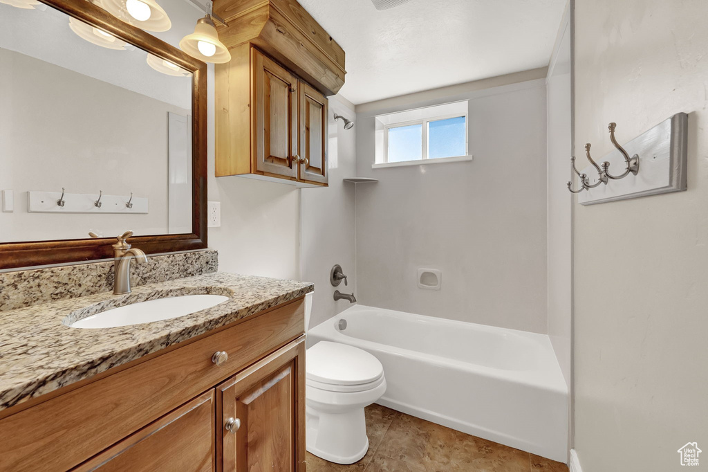 Full bathroom with shower / tub combination, tile flooring, vanity with extensive cabinet space, and toilet