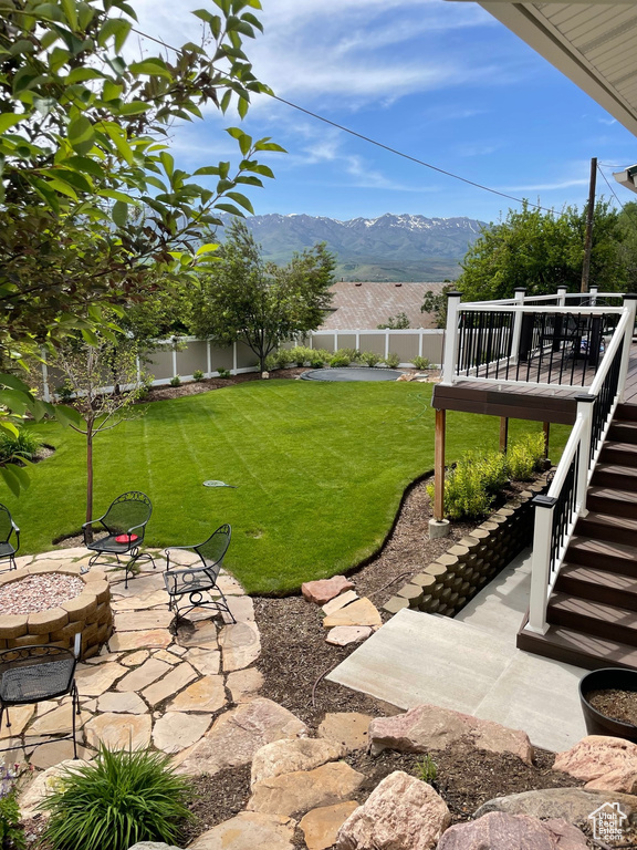 View of yard featuring a deck with mountain view and a patio area
