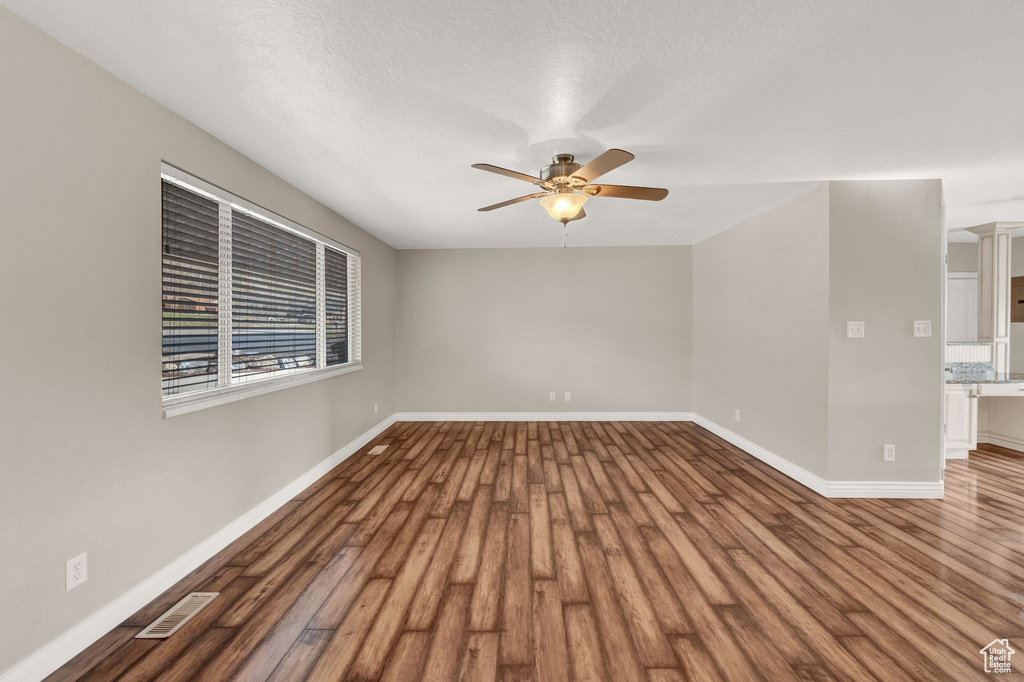 Empty room with dark wood-type flooring and ceiling fan