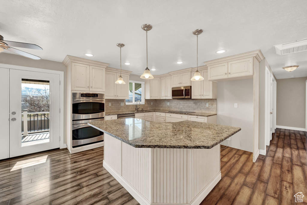 Kitchen with ceiling fan, decorative light fixtures, dark hardwood / wood-style floors, tasteful backsplash, and appliances with stainless steel finishes