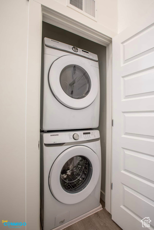 Laundry room featuring stacked washing maching and dryer and dark hardwood / wood-style floors