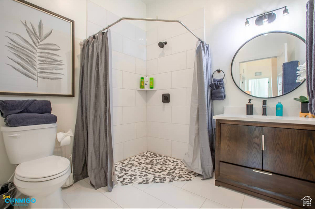 Bathroom with large vanity, toilet, tile flooring, and curtained shower