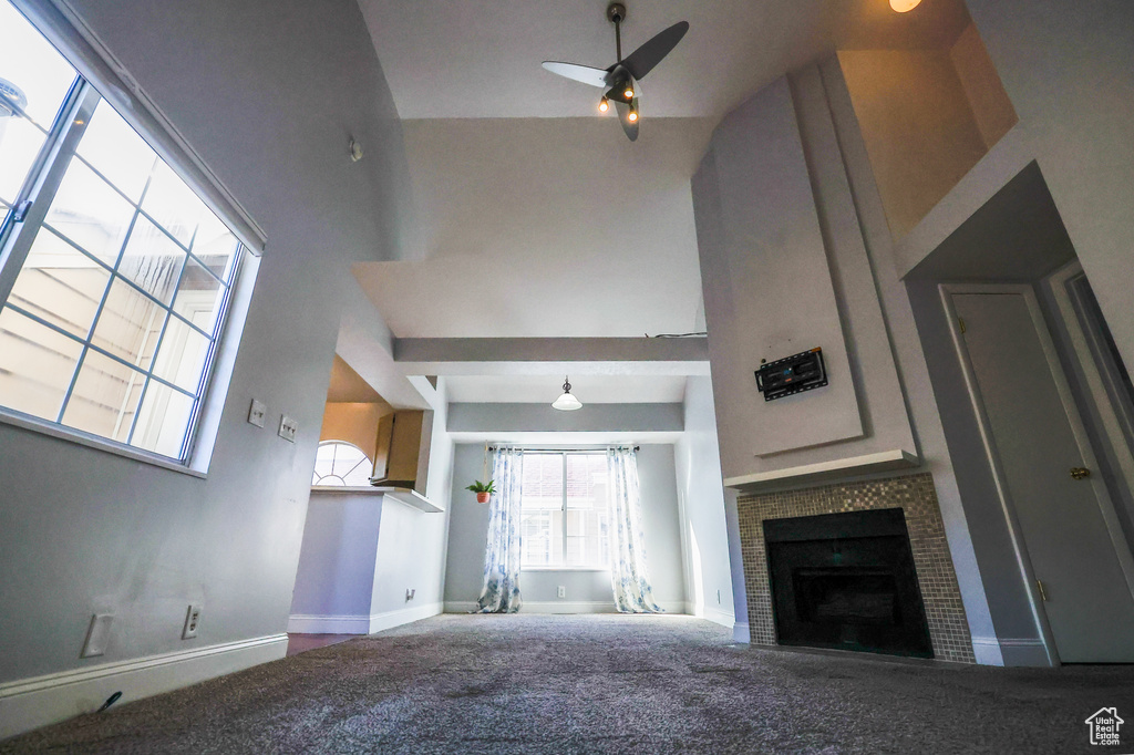 Unfurnished living room with carpet flooring, a towering ceiling, and ceiling fan