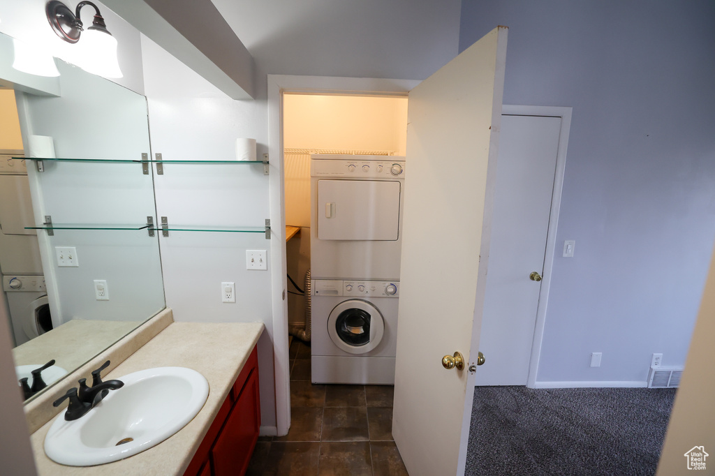 Bathroom with tile floors, stacked washer / dryer, and vanity