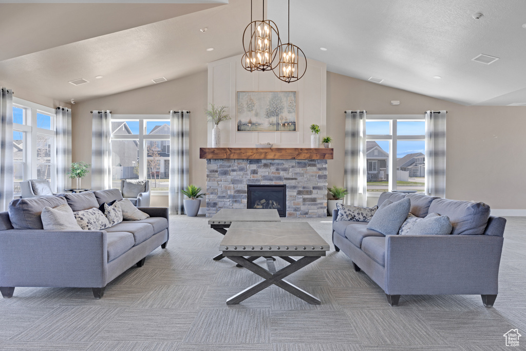 Living room featuring a notable chandelier, light carpet, lofted ceiling, and a stone fireplace