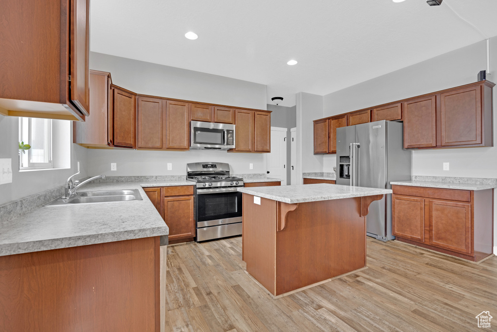 Kitchen with a kitchen island, sink, light wood-type flooring, and stainless steel appliances