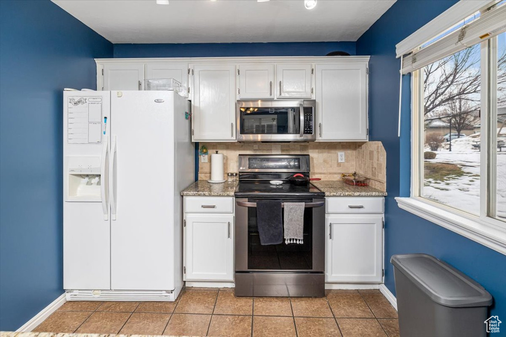 Kitchen featuring tasteful backsplash, range with electric stovetop, white cabinets, and white refrigerator with ice dispenser