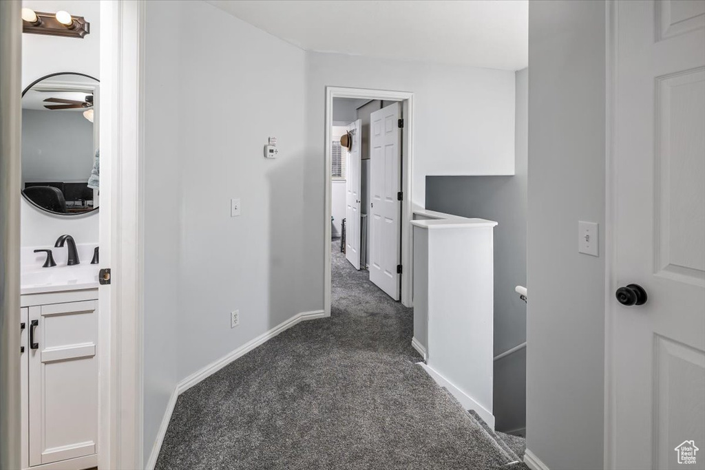 Corridor with sink and dark carpet