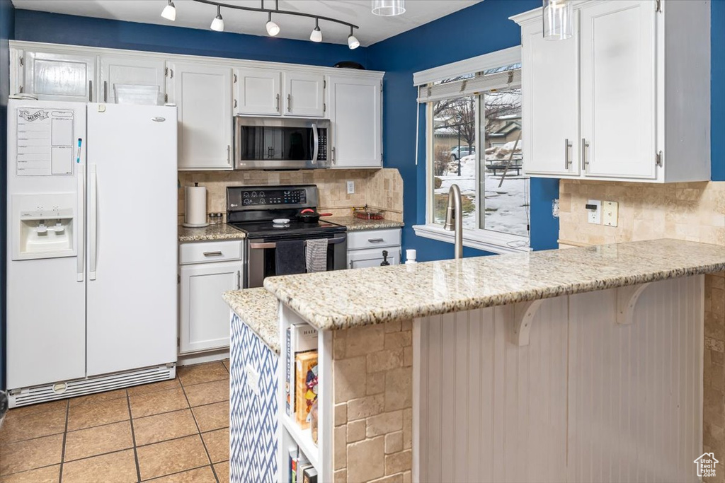 Kitchen featuring tasteful backsplash, appliances with stainless steel finishes, and white cabinets