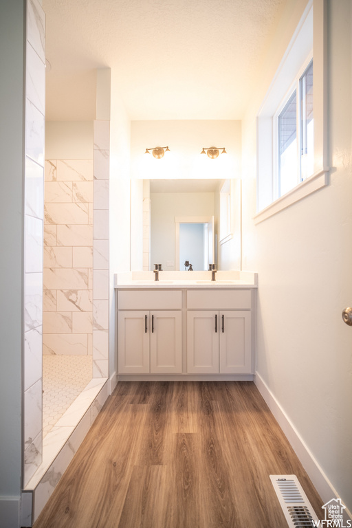 Bathroom with hardwood / wood-style floors, vanity, and tiled shower