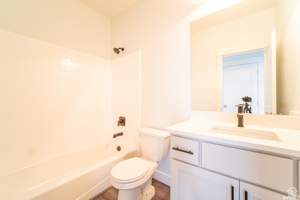 Full bathroom with wood-type flooring, oversized vanity, shower / bathing tub combination, and toilet
