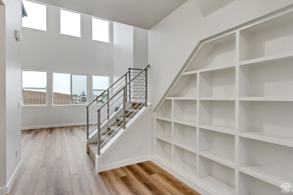 Stairs with a high ceiling and light hardwood / wood-style flooring