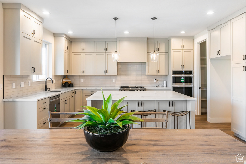 Kitchen featuring pendant lighting, backsplash, stainless steel appliances, and a center island