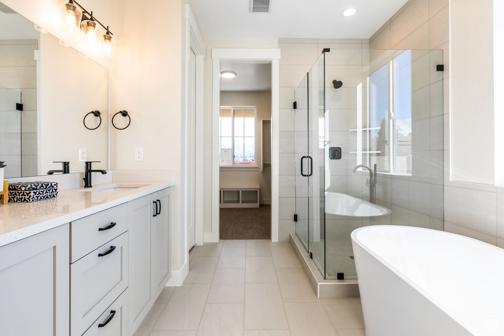 Bathroom featuring vanity, tile walls, tile floors, and plus walk in shower