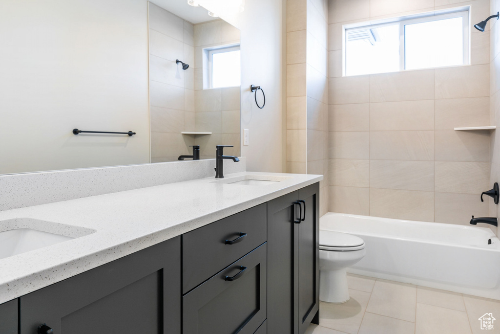 Full bathroom featuring toilet, tiled shower / bath combo, tile flooring, and plenty of natural light