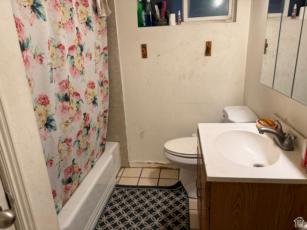 Full bathroom with shower / tub combo, toilet, vanity with extensive cabinet space, and tile flooring
