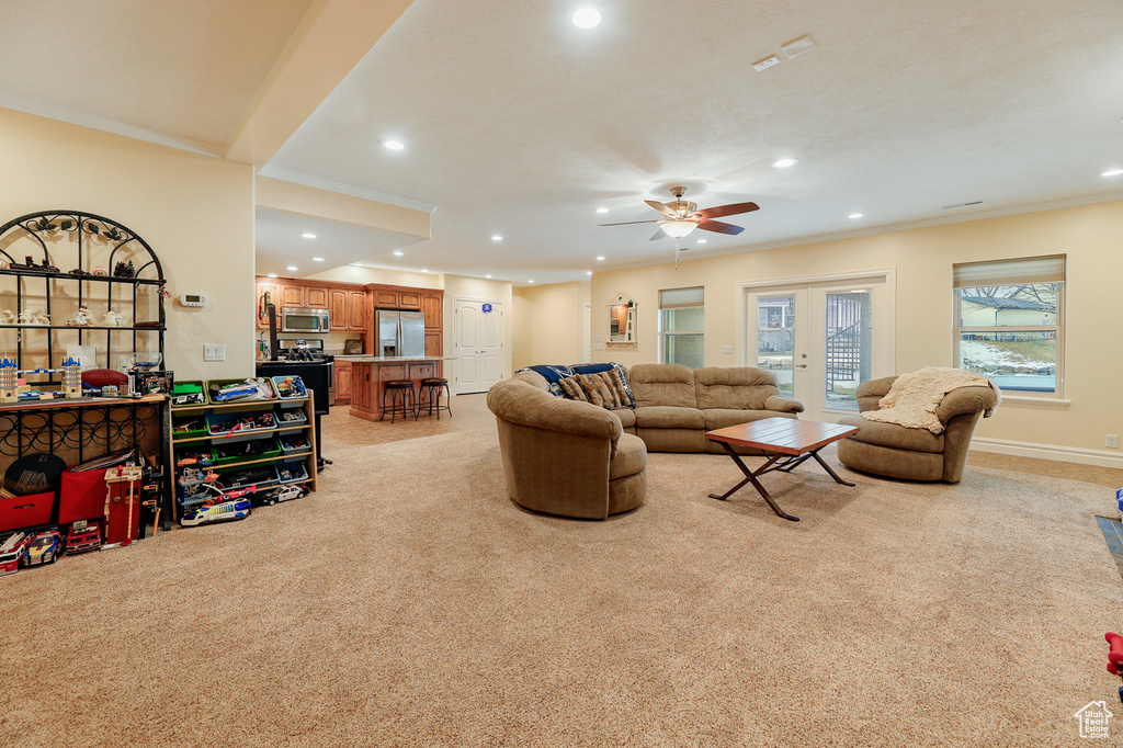 Carpeted living room with crown molding, french doors, and ceiling fan