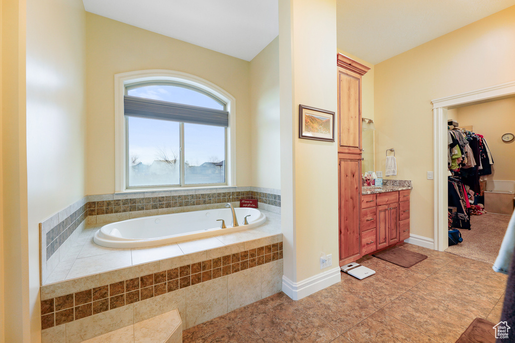 Bathroom with tile floors, vanity, and a relaxing tiled bath