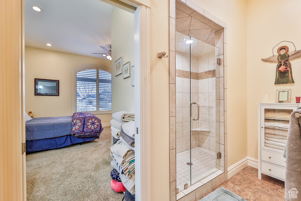 Bathroom featuring a shower with shower door, tile flooring, and ceiling fan
