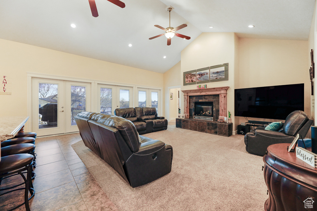 Living room featuring a tile fireplace, french doors, light tile floors, ceiling fan, and high vaulted ceiling