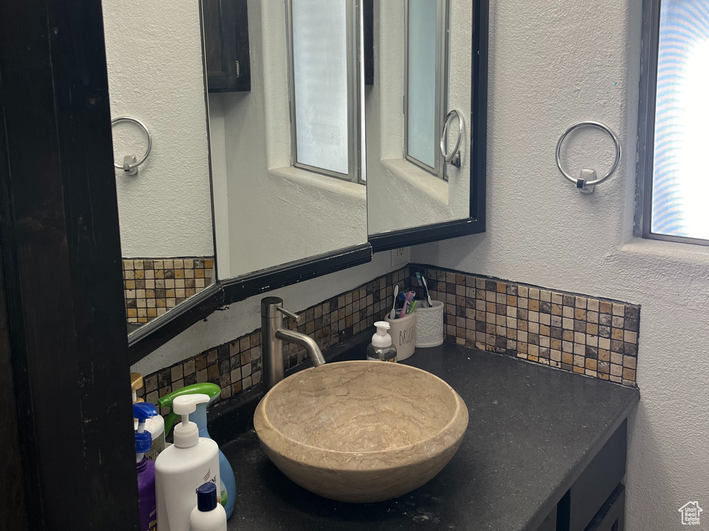Bathroom featuring an inviting chandelier, tasteful backsplash, and vanity