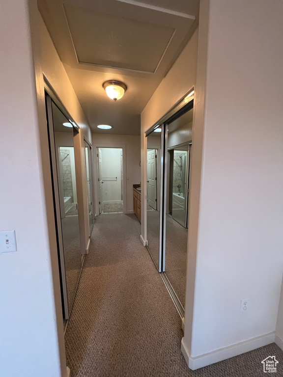 Corridor featuring dark colored carpet