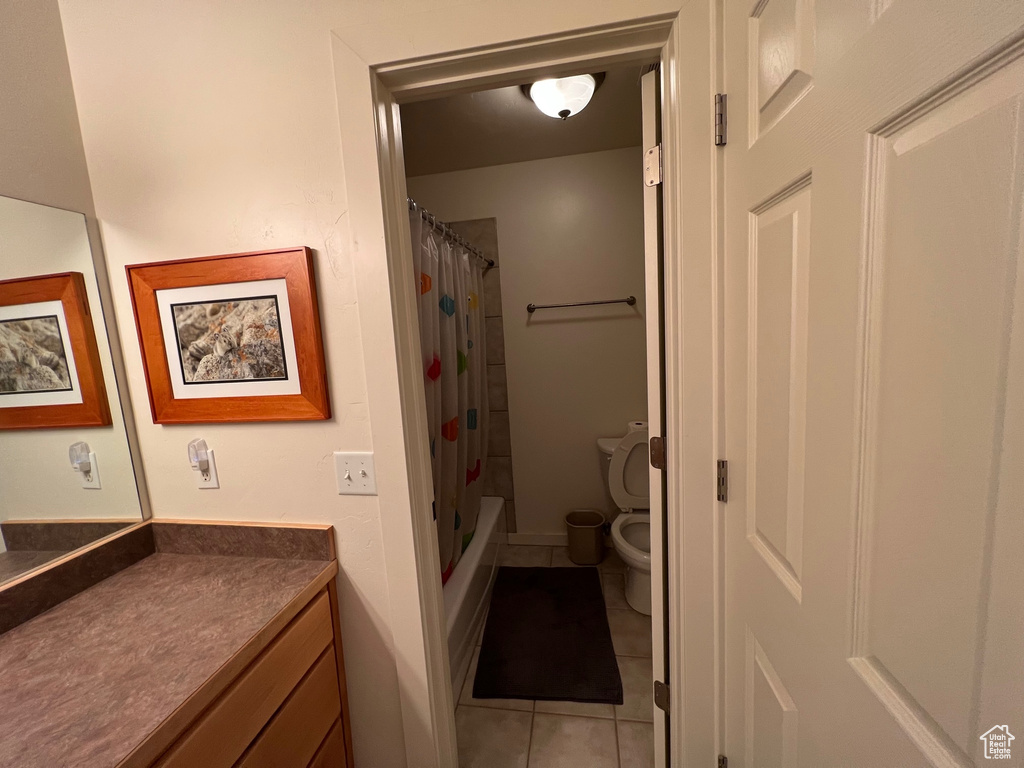 Full bathroom with shower / tub combo with curtain, toilet, vanity, and tile flooring