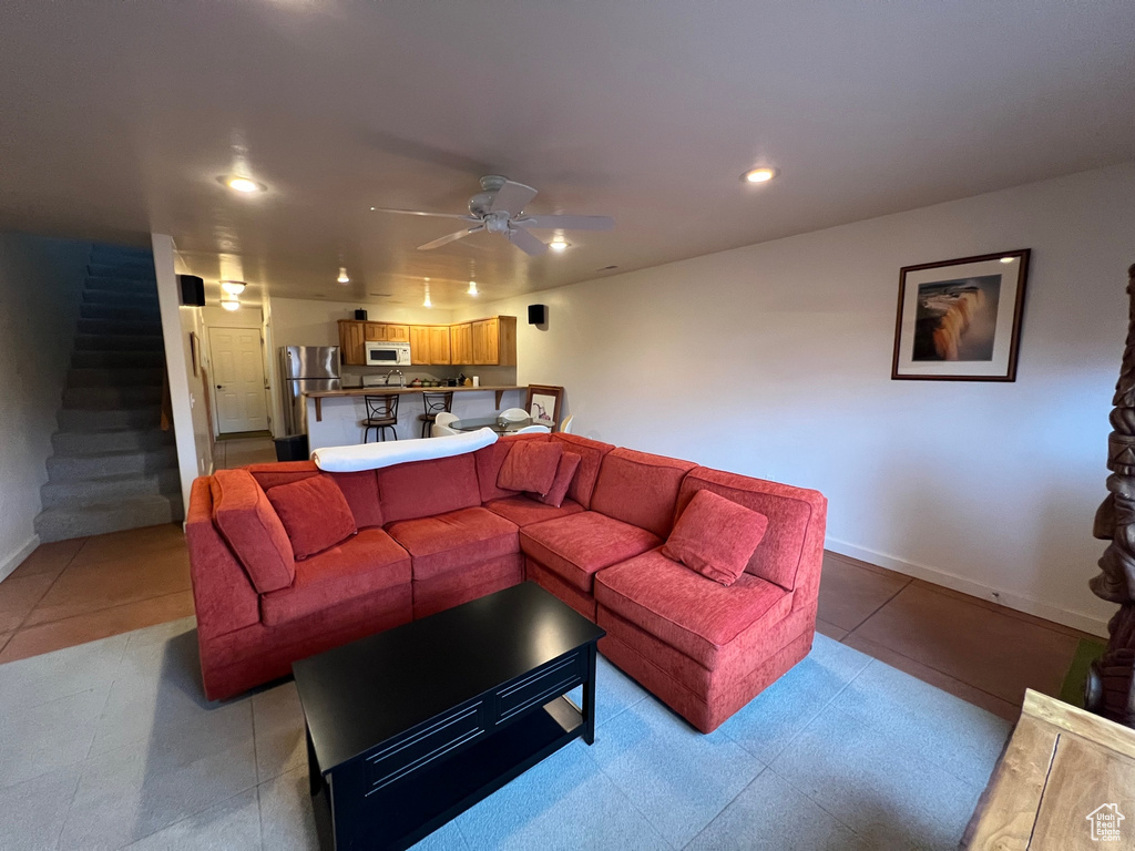 Living room with ceiling fan and light tile floors