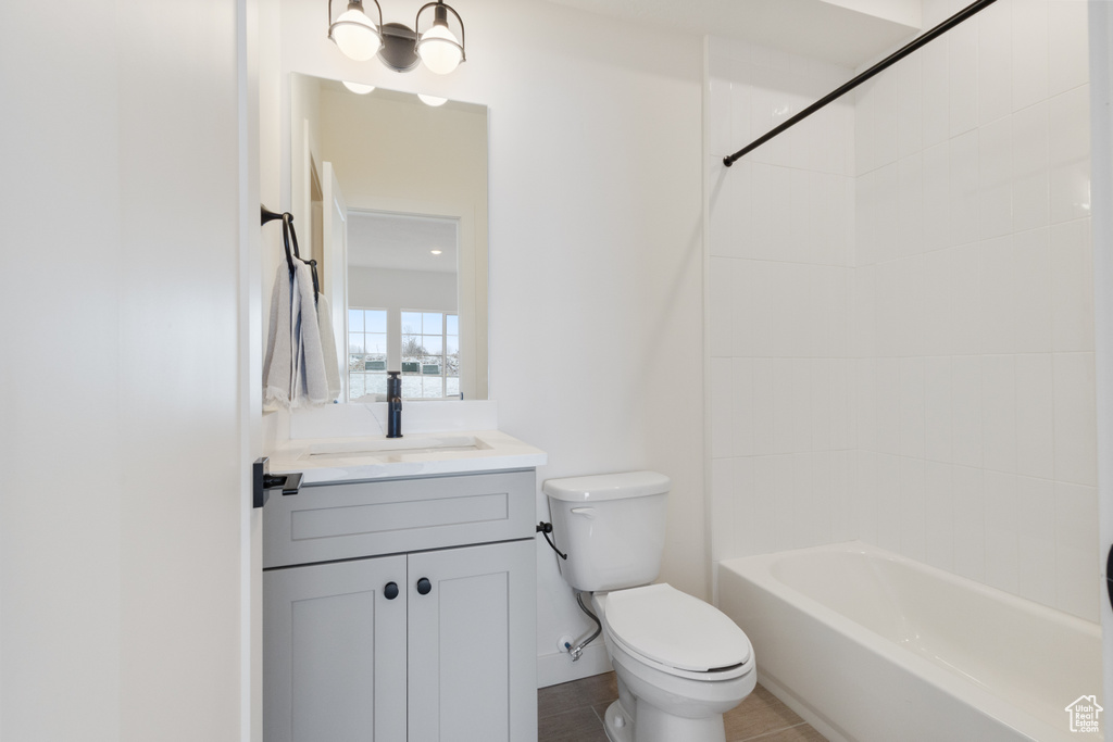 Full bathroom with tiled shower / bath, tile floors, large vanity, and toilet