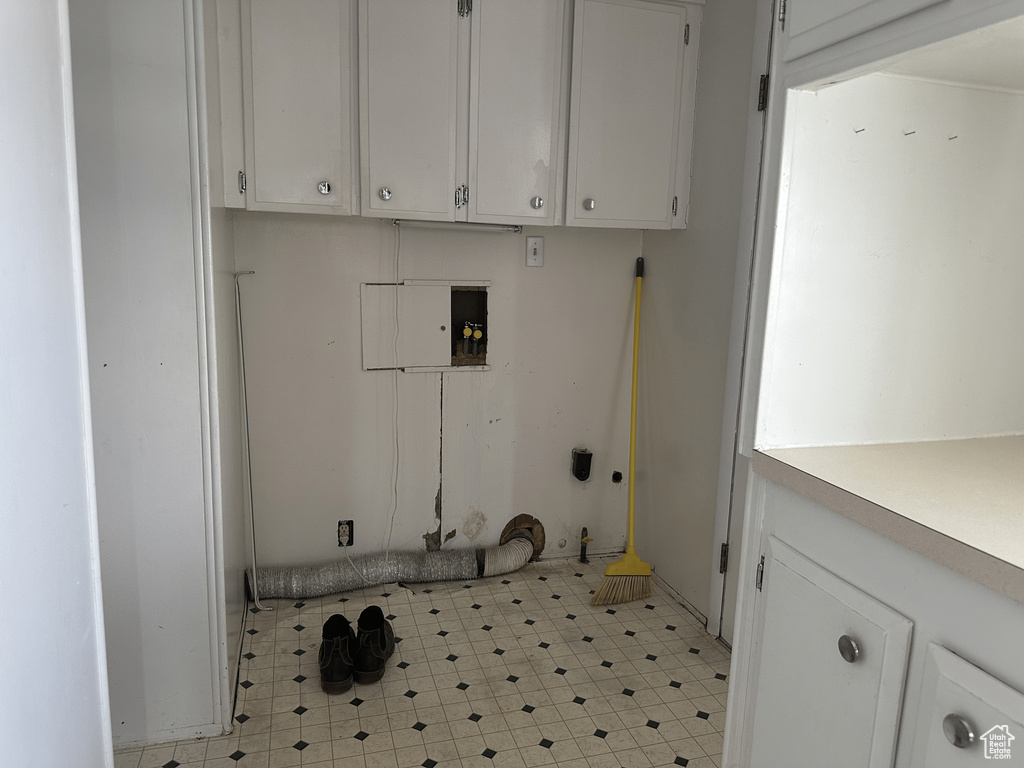 Washroom featuring washer hookup, cabinets, and light tile floors