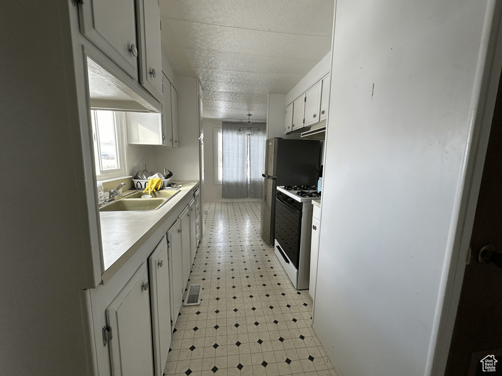 Kitchen featuring white gas stove, sink, a healthy amount of sunlight, and light tile floors