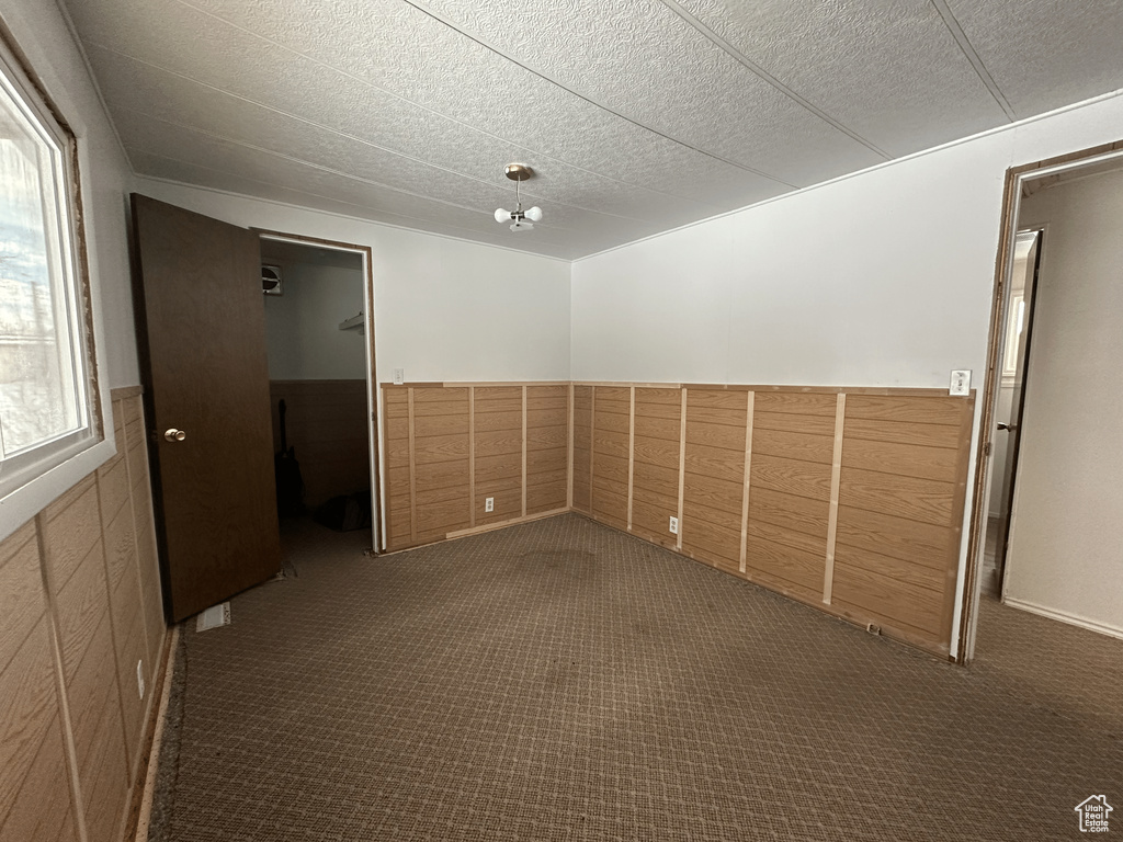 Unfurnished room with dark colored carpet and a healthy amount of sunlight