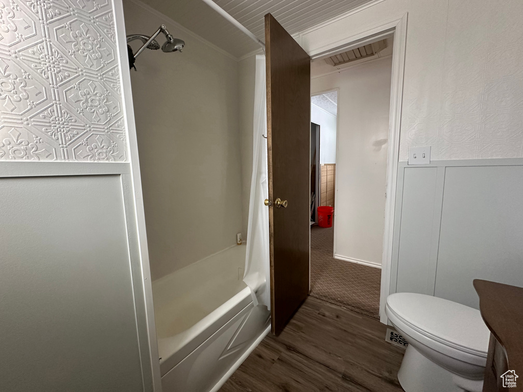 Bathroom featuring hardwood / wood-style floors, toilet, and shower / washtub combination
