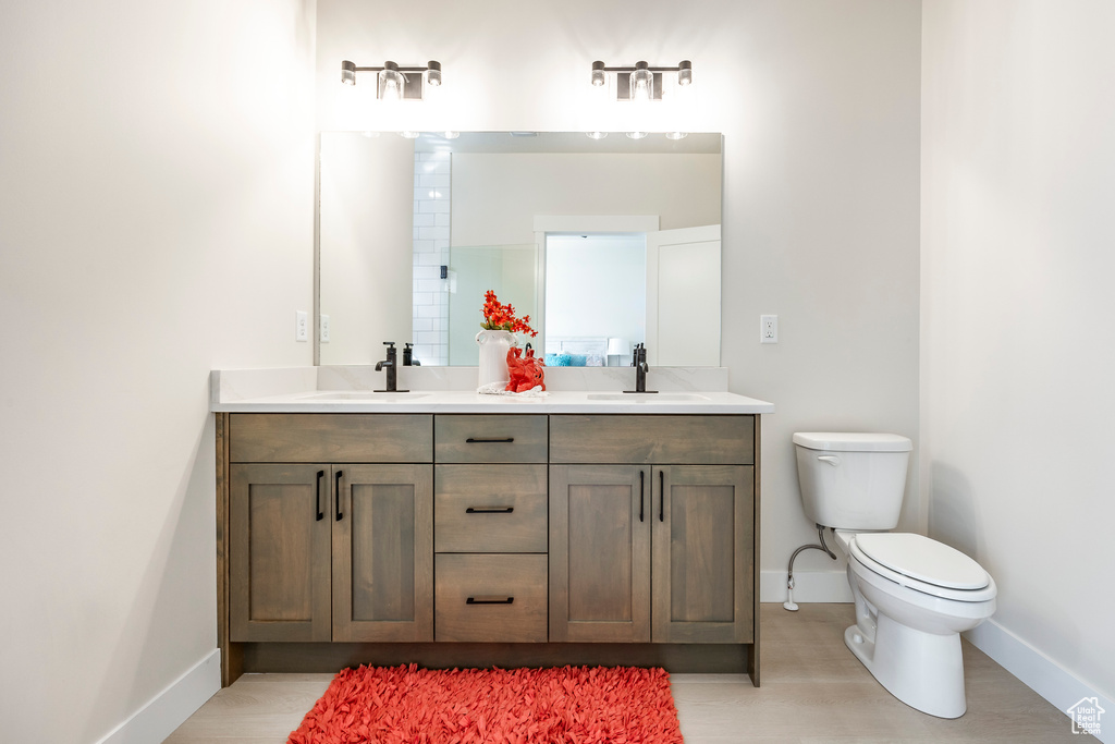 Bathroom featuring hardwood / wood-style flooring, toilet, and double sink vanity