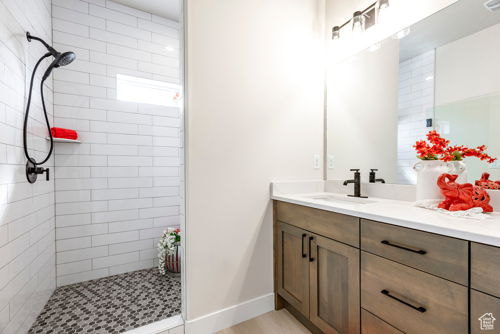Bathroom featuring hardwood / wood-style flooring, vanity, and a tile shower