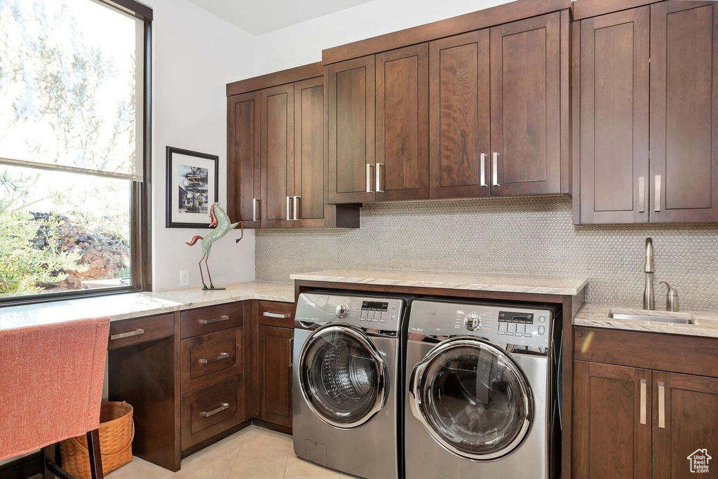 Laundry room with independent washer and dryer, light tile flooring, cabinets, and sink