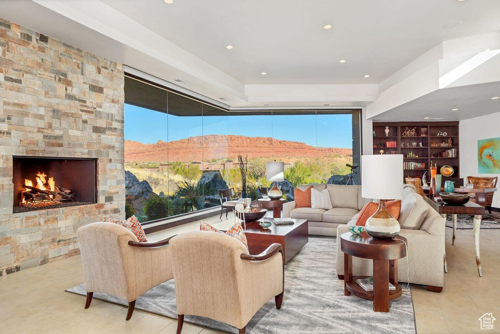Living room with a stone fireplace, light tile flooring, and a mountain view